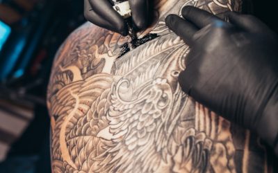 Hands of a tattoo artist wearing black gloves while holding a machine